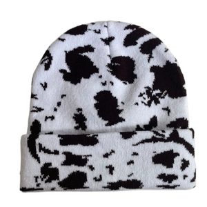 Detailed view of the soft knit texture and black and white cow print on the winter beanie