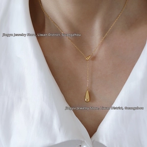Detailed view of dual water-drop tassel necklace in 18K gold plated titanium steel