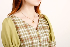 Close-up of a gold heart pendant necklace worn on the neck for Mother's Day gift
