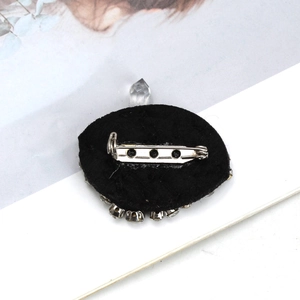Detail view of the silver metal safety pin and black felt backing on the eye brooch