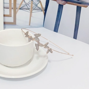 Detail of rose gold butterfly headband with sparkling white crystals on a white cup