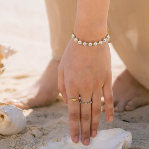 Elegant s925 silver pearl bracelet and gold rings set displayed on a sunny beach
