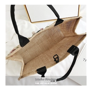 Detailed interior view of a natural linen tote bag with black handles and colorful tassels