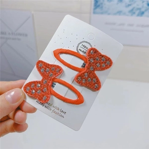Set of two orange bow hair clips featuring sparkling rhinestones on fabric base