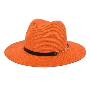 Detailed texture of orange wide brim straw hat with black leather strap and gold chain link