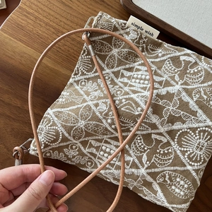 Close-up of ethnic embroidered canvas crossbody bag with intricate white floral patterns