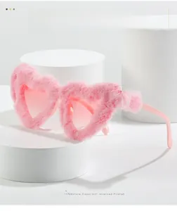 Detailed view of pink heart-shaped sunglasses with fluffy plush frame on pedestals