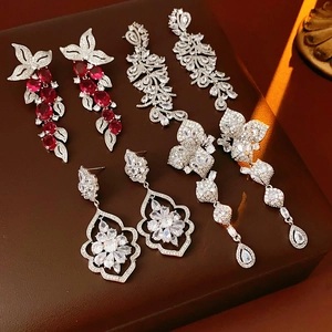 Détail de boucles d'oreilles fleurs en zircon et pampilles de pierres rouges sur cuir