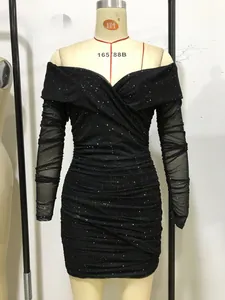 Dettaglio dell'abito arricciato con paillettes nere, scollo a barca e maniche in mesh