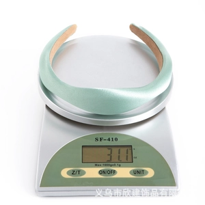 Close-up of light green sponge headband on a digital scale showing weight of 31.1g