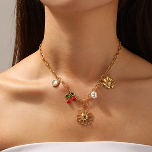 Collier doré avec breloques cerise et marguerite porté par un mannequin élégant