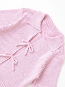 Close-up of pink ribbed knit top featuring delicate bow ties and a stylish polo collar