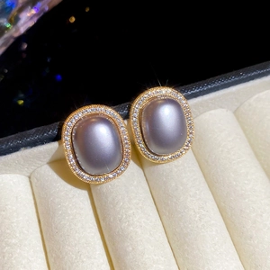 Macro detail of oval grey cat eye earrings with gold frames and zircon inlays