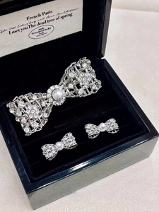 Detailed view of silver bow jewelry set with zircon paving and white pearls in velvet box