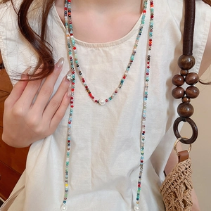 Detail of colorful crystal beads and a large white pearl on a boho style long necklace