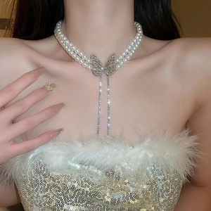 Close-up of double-layer pearl necklace with a sparkling butterfly pendant and tassels