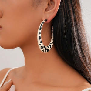 Close-up of chunky resin hoop earrings with black and white cow print on model