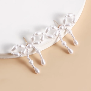 Detailed view of handmade bow-shaped pearl tassel earrings with golden metal studs
