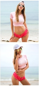 Dettaglio di t-shirt rosa attillata e pantaloncini di jeans rossi con frange in spiaggia