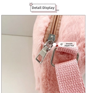 Detail of pink plush bag showing smooth metal zipper pull and woven shoulder strap