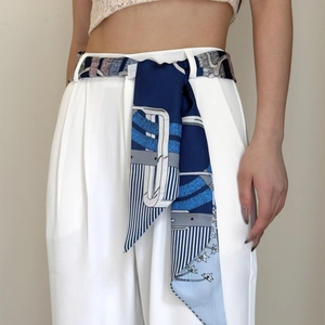 Polka dot silk scarf worn as a belt with blue star pattern on white wide-leg pants