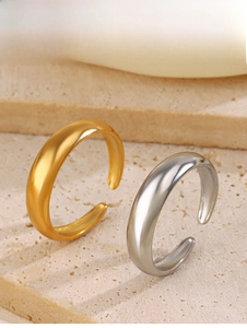 Detail view of minimalist gold and silver open rings on a textured stone surface