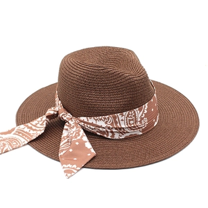 Dark brown wide brim Panama straw hat with a white paisley print scarf tied on the side