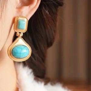 Vintage gold-plated teardrop earrings with sky blue resin stones on a model