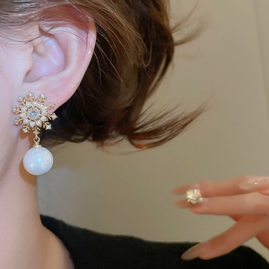 Close-up of snowflake pearl earrings featuring gold alloy and sparkling zircon details