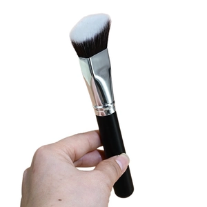 Angled foundation brush with black handle and gradient bristles shown being held
