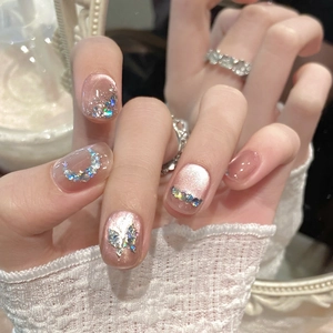 Détail macro de faux ongles faits main rose avec des papillons et des strass brillants