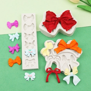 Detailed view of white silicone bow molds with colorful resin samples on green background