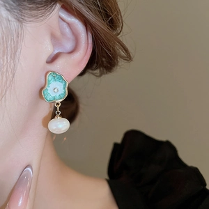 Détail de boucle d'oreille feuille de lotus avec émail vert, diamant et perle d'imitation