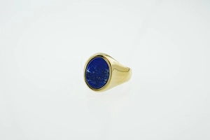 Macro detail of men's gold signet ring featuring a polished oval blue lapis lazuli stone