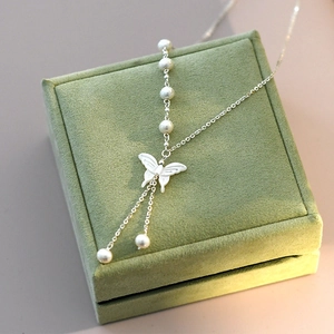 Elegant silver butterfly necklace with white shell pearl on a green velvet jewelry box