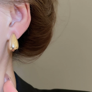 Close-up of golden teardrop earrings on model with polished metallic finish
