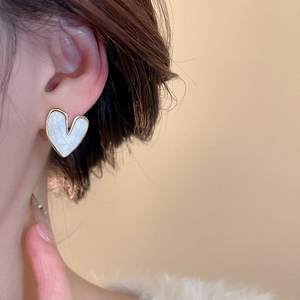 Detail of heart stud earring featuring gold trim and white marble texture inlay on ear