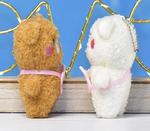 Side view of 4-inch brown and white plush bear keychains with pink ribbon details