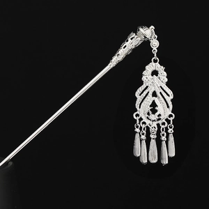 Detail of silver Hmong hair pin with intricate hollow carvings and hanging tassels