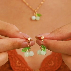 Macro shot of cherry-themed necklace and earrings set with green translucent beads