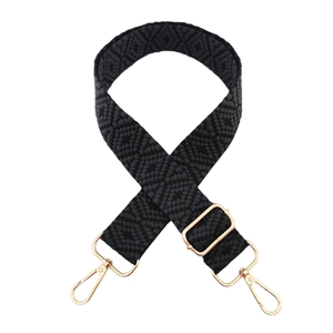 Detail of adjustable bag strap with black geometric jacquard pattern and gold metal hooks