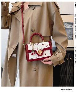 Detail view of cherry print crossbody bag with floral clasp and twisted handle