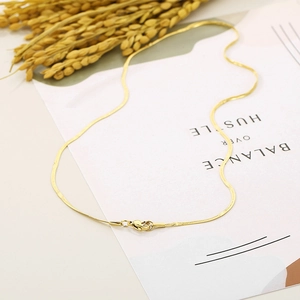 Flat lay of 1.5mm gold titanium steel snake chain necklace on minimalist card background