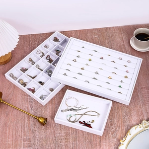 White leather jewelry display tray set for rings and earrings on a wooden desk