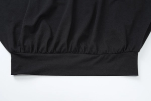 Détail macro de l'ourlet froncé élastique et des coutures sur ce haut noir en maille