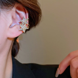 Close-up of a gold star ear cuff with sparkling zircons worn on a model ear