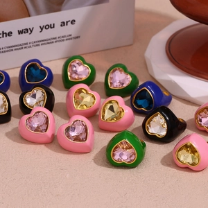 Close-up of colorful heart-shaped enamel rings with faceted gemstones in 18K gold plating