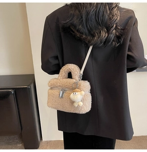 Detailed view of beige faux shearling square handbag with fluffy charm and zipper