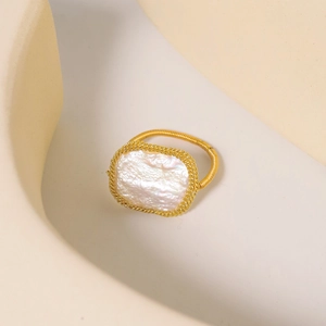 Close-up of golden woven ring featuring a large pink baroque pearl on a soft background
