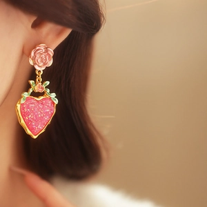 Detailed close-up of a pink resin flower earring with a glittery heart-shaped pendant